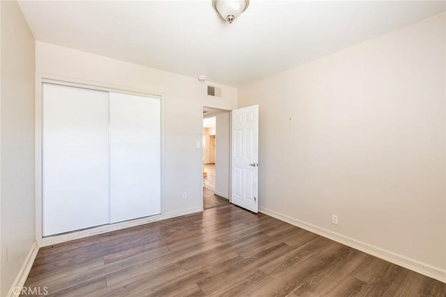 unfurnished bedroom with dark hardwood / wood-style floors and a closet