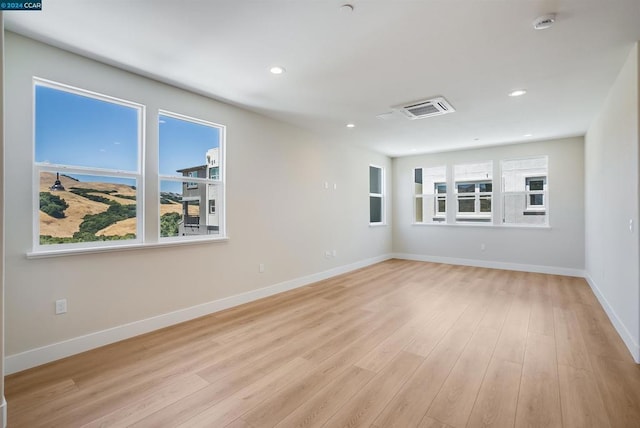 spare room featuring a healthy amount of sunlight and light wood-type flooring