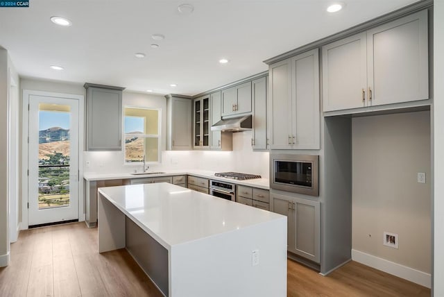 kitchen with a kitchen island, appliances with stainless steel finishes, sink, and light hardwood / wood-style flooring