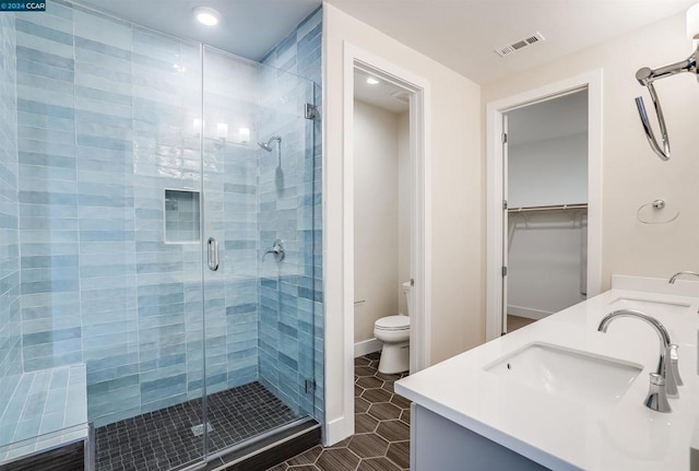 bathroom featuring tile patterned floors, toilet, a shower with shower door, and vanity