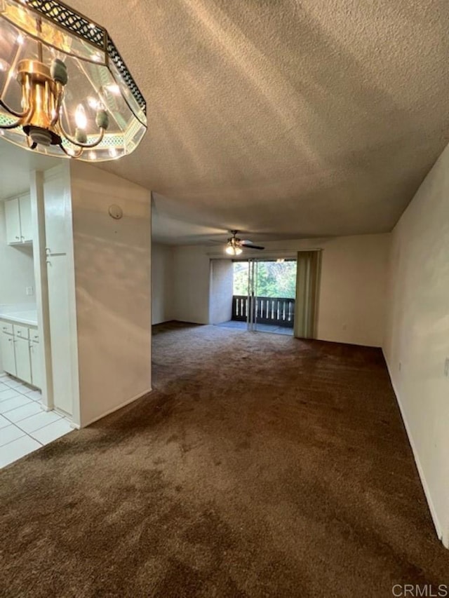 interior space featuring ceiling fan with notable chandelier and a textured ceiling