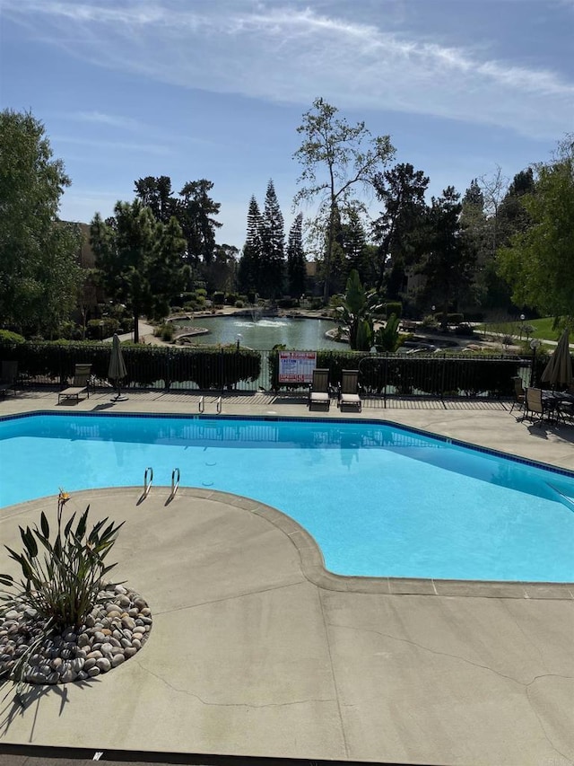 view of swimming pool featuring a patio area and a water view