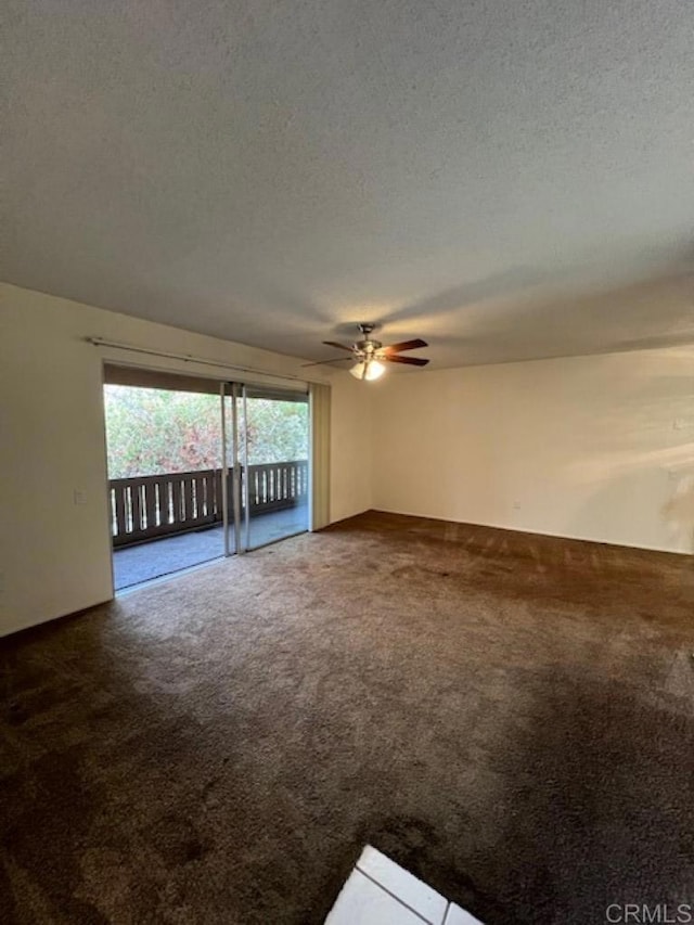 spare room with dark colored carpet, ceiling fan, and a textured ceiling