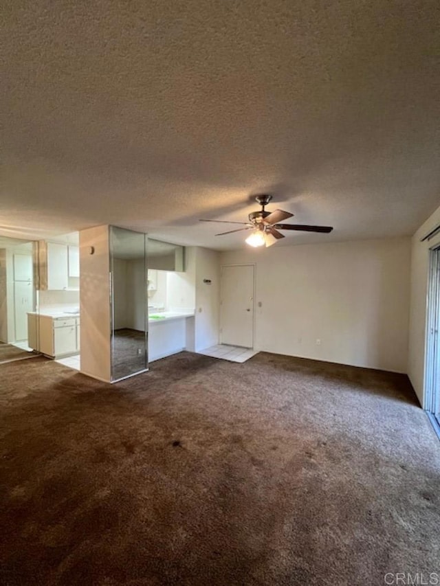 unfurnished living room featuring ceiling fan, carpet, and a textured ceiling