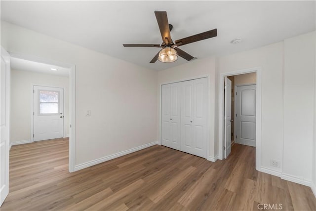 unfurnished bedroom featuring ceiling fan, light wood-type flooring, and a closet