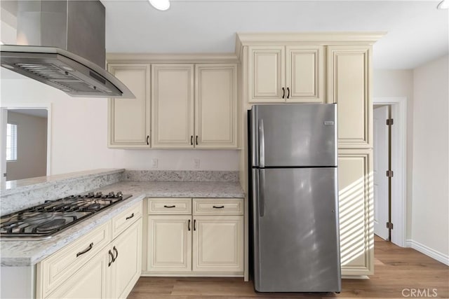 kitchen with cream cabinetry, light wood-type flooring, stainless steel appliances, and extractor fan