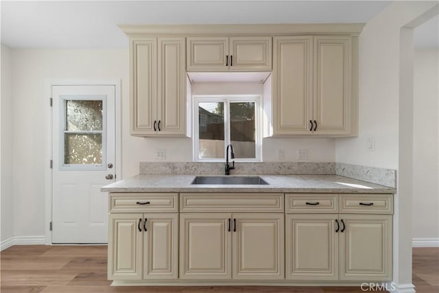 kitchen featuring cream cabinets, light hardwood / wood-style flooring, and sink