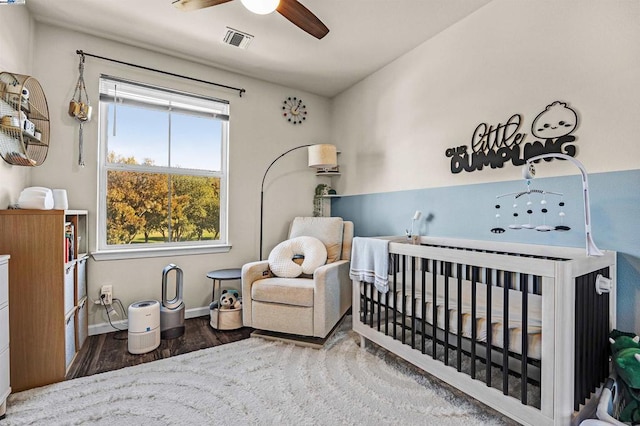 bedroom featuring ceiling fan, hardwood / wood-style flooring, and a nursery area