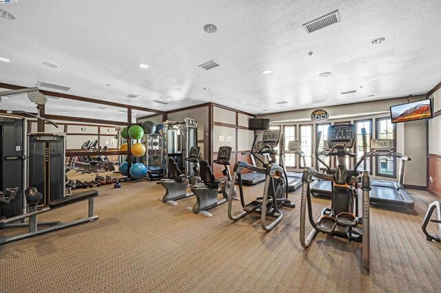 gym with a textured ceiling and carpet floors