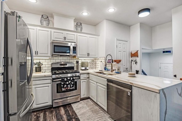 kitchen with kitchen peninsula, appliances with stainless steel finishes, and white cabinetry