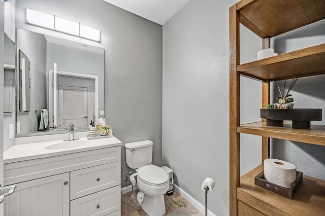 bathroom with toilet, vanity, and tile patterned flooring