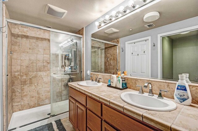 bathroom with a textured ceiling, an enclosed shower, and vanity