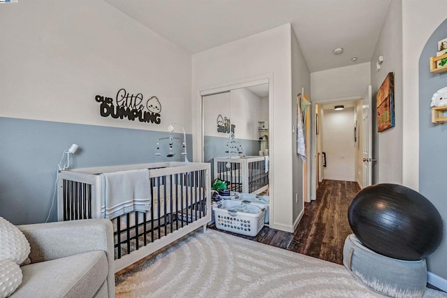 bedroom with a crib and dark hardwood / wood-style floors