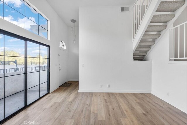 interior space featuring a high ceiling and light wood-type flooring