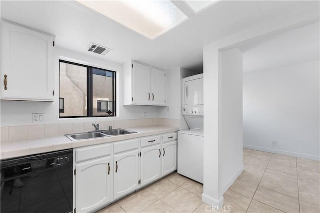 kitchen featuring white cabinets, black dishwasher, stacked washer and clothes dryer, and sink