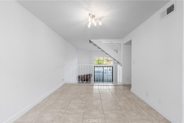 unfurnished living room with a chandelier and light tile patterned floors