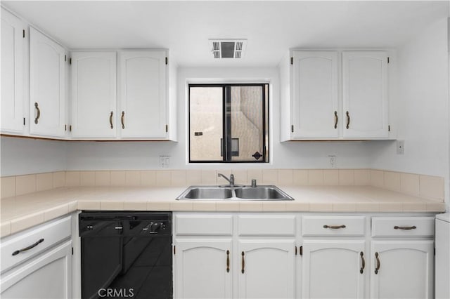 kitchen featuring black dishwasher, white cabinetry, tile counters, and sink