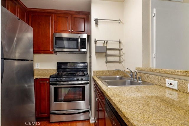 kitchen with light stone countertops, sink, wood-type flooring, and appliances with stainless steel finishes