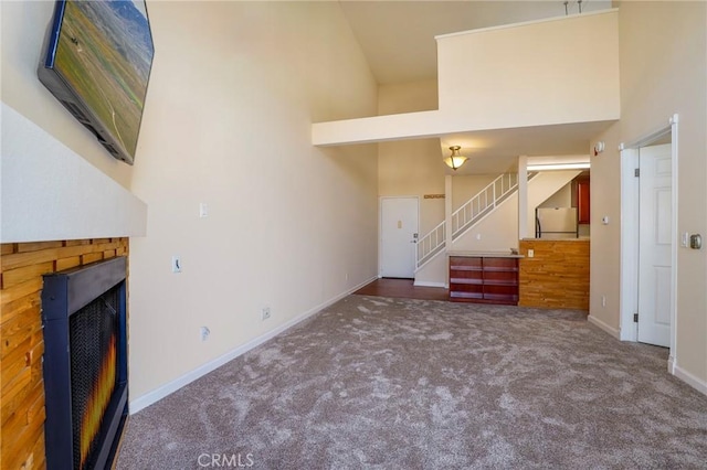 unfurnished living room with carpet flooring and a towering ceiling