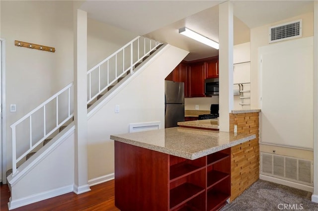 kitchen with appliances with stainless steel finishes, dark hardwood / wood-style flooring, and light stone counters