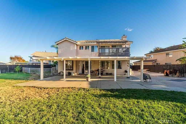 back of property with a yard, a patio area, and a balcony