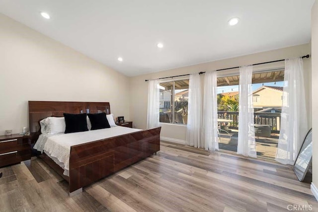 bedroom with hardwood / wood-style flooring, access to outside, and vaulted ceiling