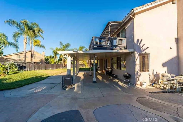 exterior space with a patio, a balcony, and a lawn