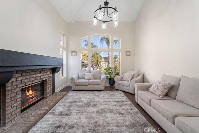 living room with a fireplace, high vaulted ceiling, a chandelier, and dark hardwood / wood-style floors