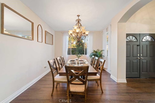 dining area with dark hardwood / wood-style floors and an inviting chandelier