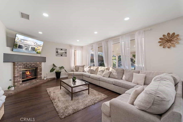 living room with dark wood-type flooring and a brick fireplace