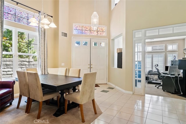 tiled dining space featuring a towering ceiling and an inviting chandelier