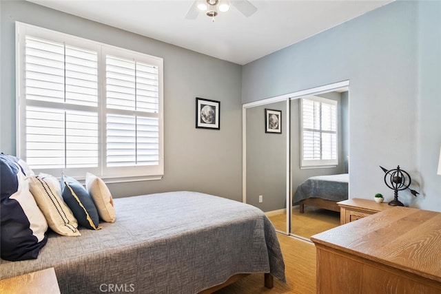 bedroom with light wood-type flooring, a closet, and ceiling fan