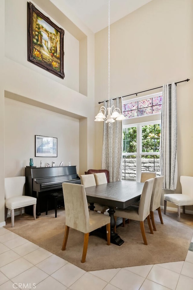 dining space with light tile patterned floors, a towering ceiling, and an inviting chandelier