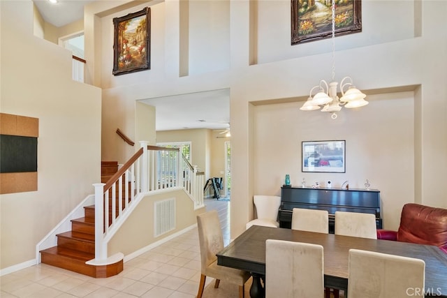 tiled dining area featuring a towering ceiling and ceiling fan with notable chandelier