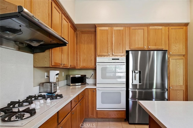 kitchen with light tile patterned floors, stainless steel appliances, and ventilation hood