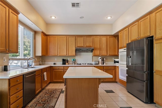 kitchen with sink, a kitchen island, stainless steel appliances, and light tile patterned floors