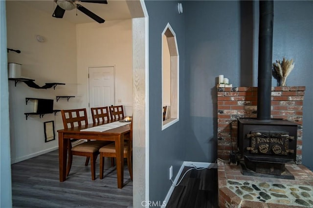 dining room with a wood stove, ceiling fan, and dark hardwood / wood-style floors