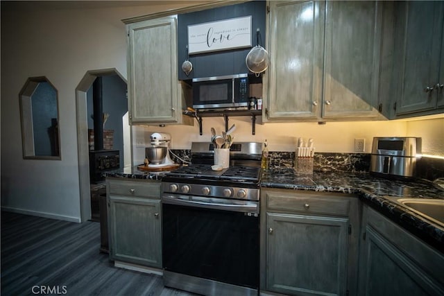 kitchen featuring appliances with stainless steel finishes, dark hardwood / wood-style floors, and dark stone counters