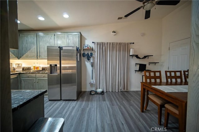 kitchen featuring wood-type flooring, stainless steel fridge with ice dispenser, ceiling fan, and dark stone countertops