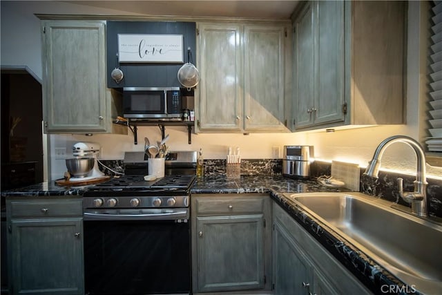 kitchen with sink, gray cabinetry, stainless steel appliances, and dark stone counters