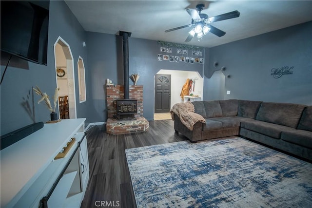 living room featuring ceiling fan, dark hardwood / wood-style floors, and a wood stove