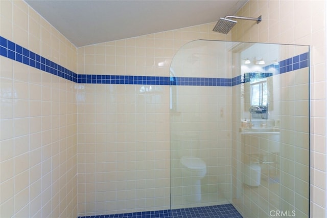 bathroom featuring lofted ceiling and tiled shower