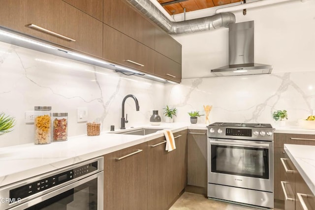 kitchen featuring light stone countertops, sink, wall chimney exhaust hood, stainless steel appliances, and tasteful backsplash