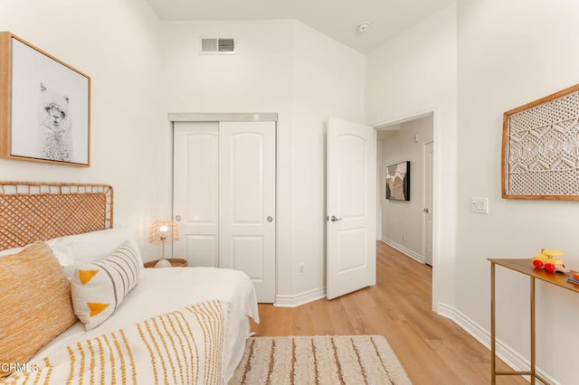 bedroom featuring a high ceiling, light hardwood / wood-style floors, and a closet