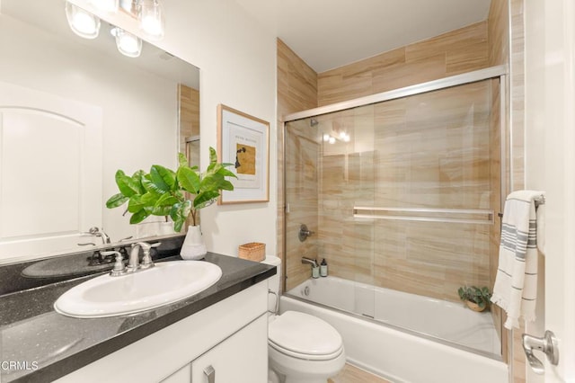 full bathroom featuring toilet, combined bath / shower with glass door, and vanity