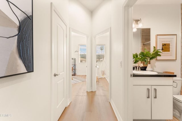 corridor with sink and light wood-type flooring