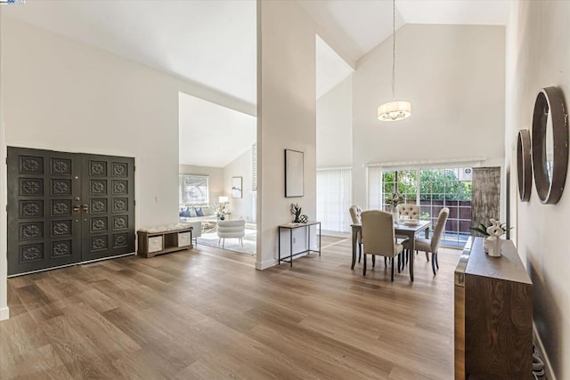 dining space with hardwood / wood-style floors and high vaulted ceiling