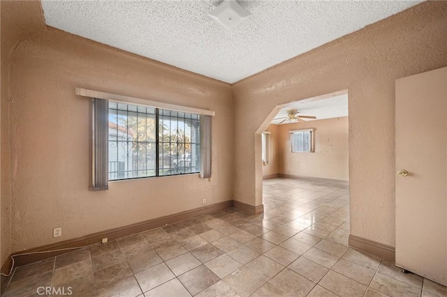 unfurnished room with ceiling fan and a textured ceiling