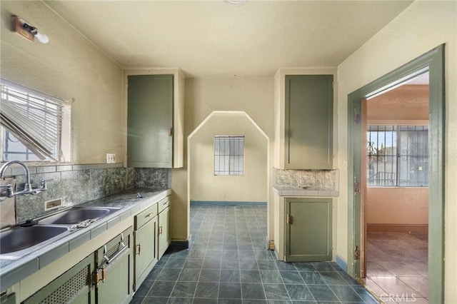 kitchen with tasteful backsplash, green cabinets, and sink