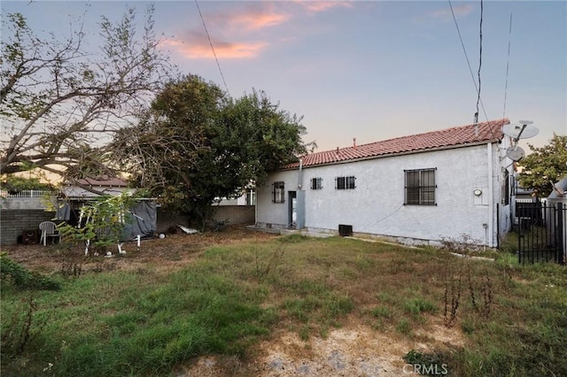 back house at dusk with a lawn